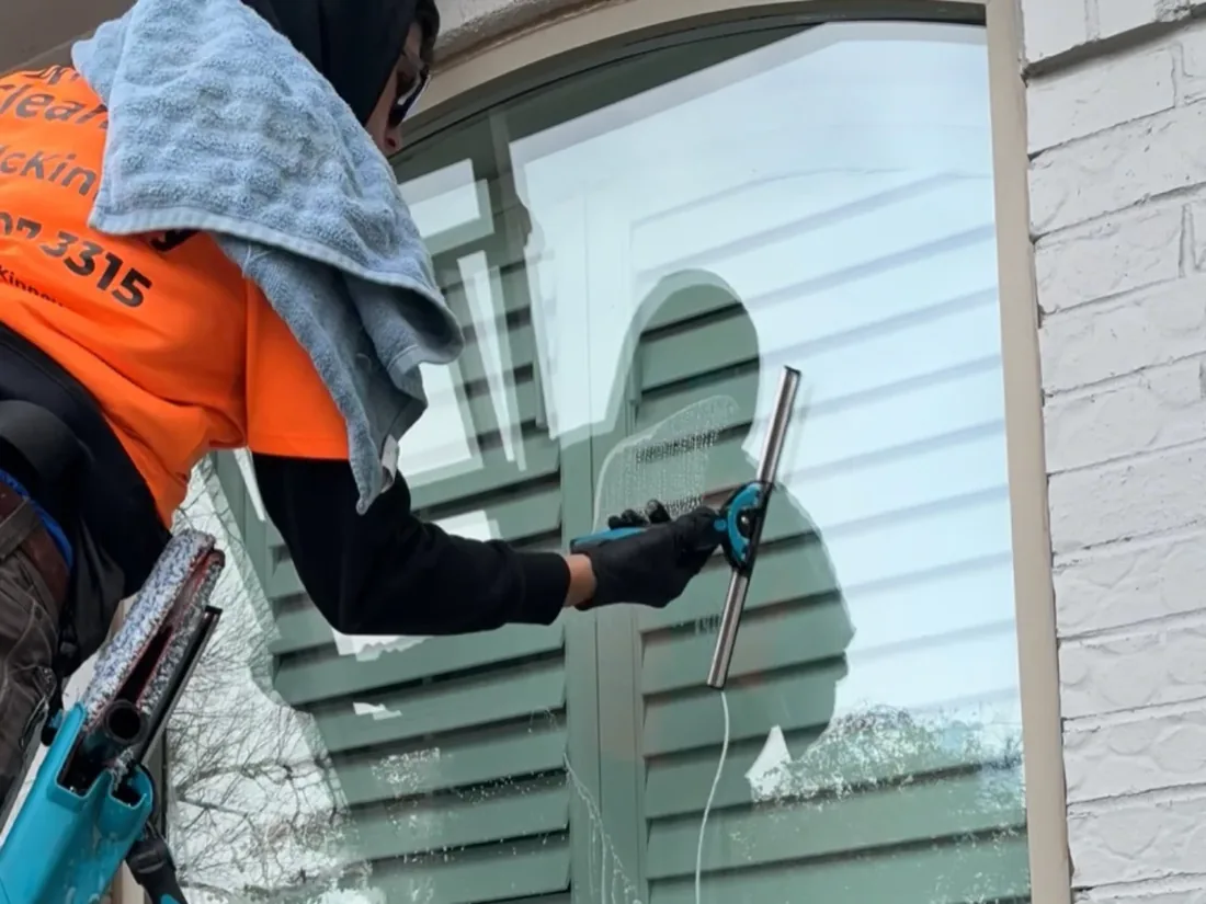 Squeegee cleaning exterior window in McKinney, TX